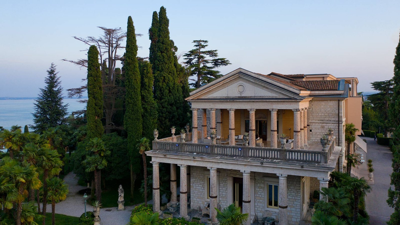 The late-19th-century neoclassical villa at the heart of Villa Cortine Palace, seen from its own park above Lake Garda.