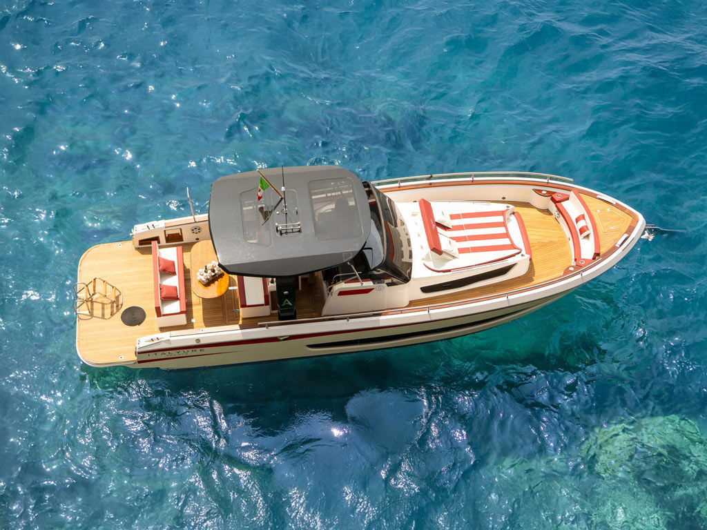 Boat trips Amalfi: Italyure Luna Rossa drone aerial view showing teak stern platform, dining area and red white design on blue sea