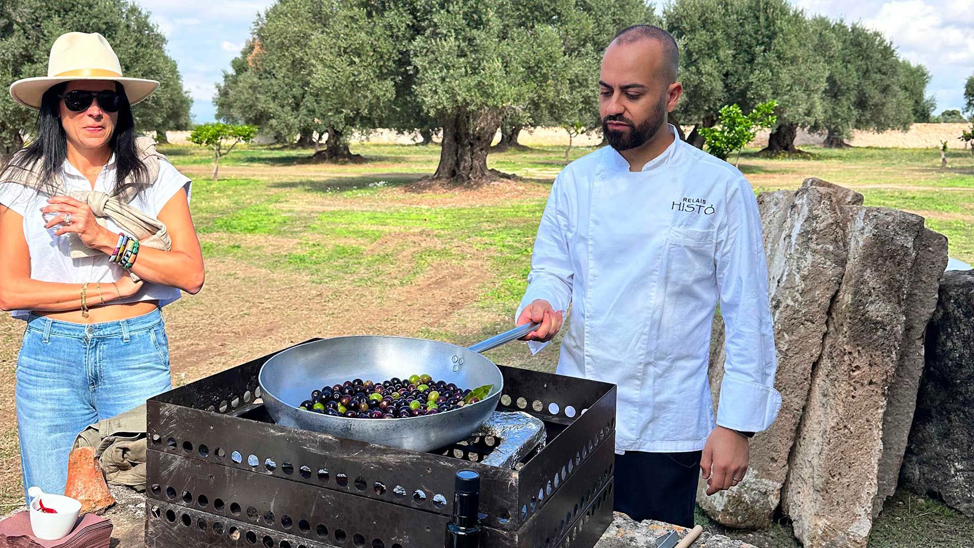 Relais Histò chef cooking black olives outdoors among the centuries-old olive trees of the estate